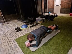Personal training aan huis klant voert de plank uit